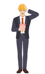 Businessman in construction helmet holding a piggy bank and grabbed his head