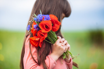 Naklejka premium red poppies in the hands of a girl