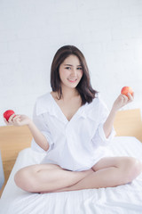 Portrait of Asian woman smiling and holding red apple on bed