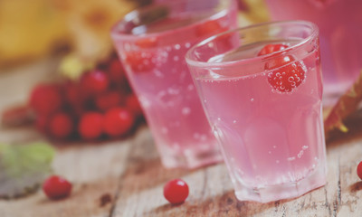Pink cocktail with viburnum, cranberry and mountain ash on an autumn background with yellow leaves and berries, selective focus and toned image