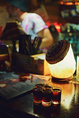 five full shots on the bar. bartender blurred in the background