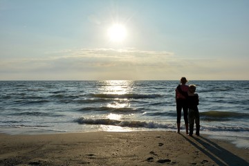 Zwei Kinder von hinten stehen umschlungen vor dem Meer
