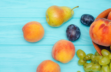 Pear, a peach in plate on a mint wooden table. Table with different fruits.