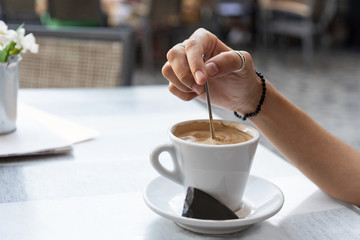 Young woman stirring a coffee