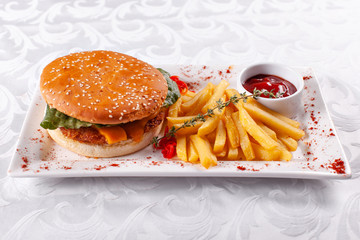 Fast food restaurant menu. Home made hamburger with the beef patties, onion, tomato, lettuce and cheese. Fresh burger close-up. Garnished with golden French fries potatoes