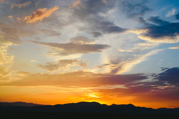 Beautiful sunset with the sun of orange tones behind the mountains and deep blue sky