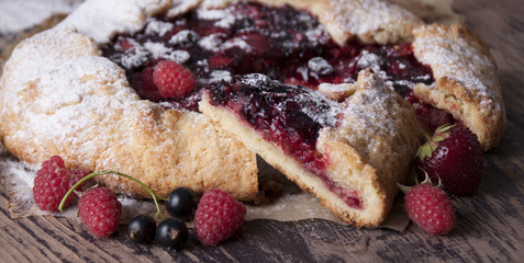 Galette with berries raspberries, strawberries and black currants with sugar powder