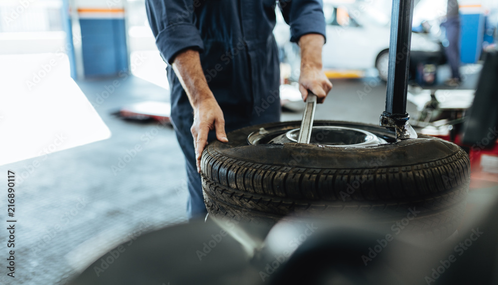 Wall mural Hands of mechanic removing car tire on machine