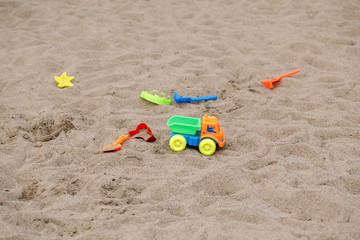 Many different plastic colourful children toys lying on ground on playground. Forgotten baby sand molds left outside.