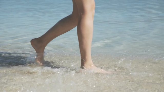Unrecognizable female bare lags walks in the blue sea