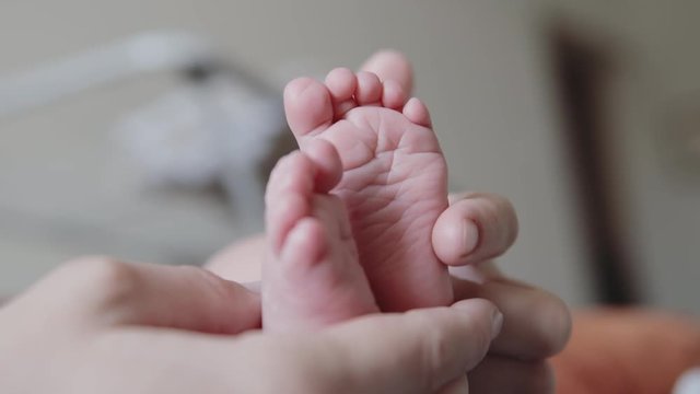 Young mother gently stroking the legs of her newborn baby