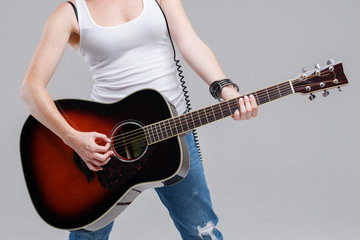 Closeup of young woman hands playing acoustic guitar at the studio