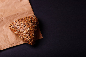 Rye bun with seed on paper. Black background