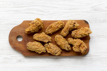 Chicken wings on a wooden board over white wooden background, top view. From above, overhead.