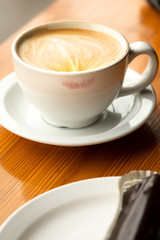 Close up on a cafe latte in a white cup with lipstick lip marks