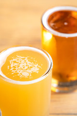 Macro close up on the foamy surface of an unfiltered pale ale, with a beer in the blurry background