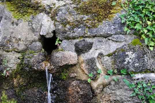Nascente de &aacute;gua - &aacute;gua de uma nascente a sair por um furo num muro em pedras - ambiente de montanha - &aacute;gua a correr