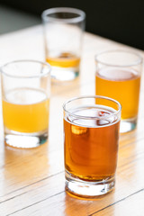 Flight of beer in taster glasses on a wood table