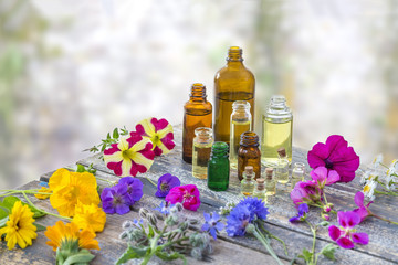 essential oil bottles, and perfume from medicinal plant in mortar surrounded by petals on timbered background