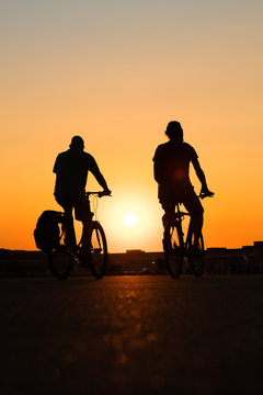 two people on bicycle with sunset sky background