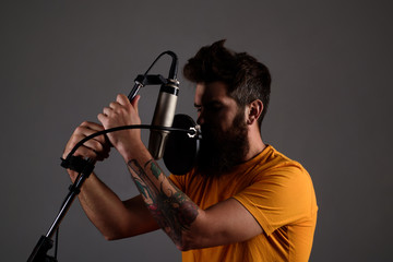 Bearded man singing with microphone. Music. Brutal bearded guy sing in microphone. Show business. Recording studio. Transmitter. Singing. Music and leisure concept. Silhouette.