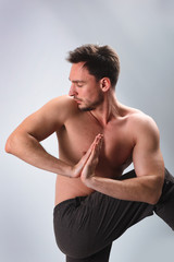 Obraz premium Calm peaceful young bearded Caucasian yoga instructor posing shirtless and barefooted in white studio, stretching. Attractie man practicing advanced yoga. A series of poses. Guy doing lunge exercise.