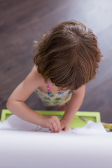 Fototapeta premium portrait of a young beautiful kid girl drawing on the blackboard at home. Happiness and lifestyle indoors. Summer. Top view