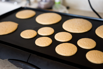 Cooking wheat pancakes for american breakfast on black griddle