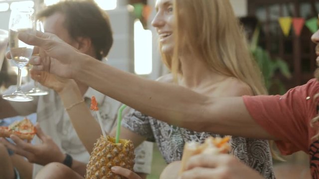 Happy group of people making a toast, having fun, smiling, enjoying picnic party with drinks outdoors together. Young friends celebrating birthday. Holiday celebration festive party. Teenage lifestyle