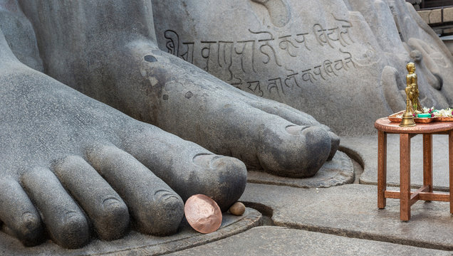 Shravanabelagola, Karnataka, India - November 1, 2013: closeup of giant blue gray granite feet of Bhagwan Bahubali. Props such as brown table and copper shield show the giant size of the statue.