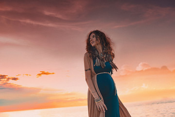 happy pregnant woman walking on a field at sunset