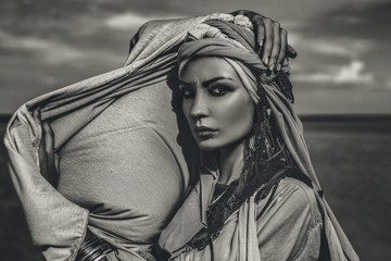 young stylish woman with fashionable boho accessories on the beach windy time. Black and white