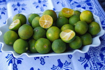 Kalamansifrüchte in Schale auf blauer Batikdecke