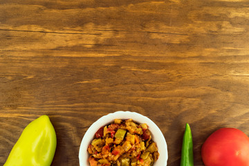 Cooked cold vegetable appetizer of stewed vegetables on vegetable oil for vegetarians in white porcelain plate on wood background next to whole fruits.