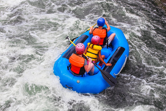 Three people in a raft in white water rapids