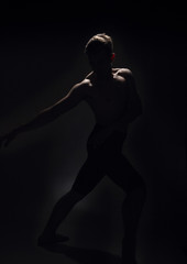 Fototapeta na wymiar one ballet dancer, dark black background, backlit backlighting.