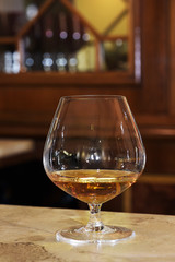 Glass with dose of brandy on bar counter