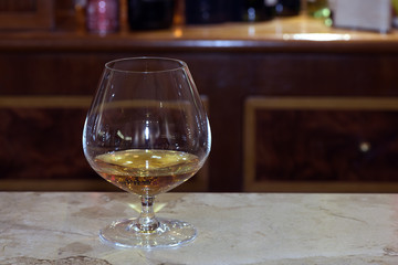 Glass with dose of brandy on bar counter