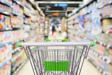 supermarket shelves aisle with empty shopping cart defocused interior blur bokeh light background
