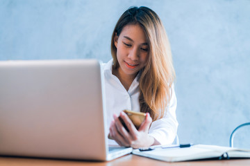 Young asian woman working with the laptop on a desk with her smile. Young asian woman working on weekend with her laptop in a warm sunlight day. Laptop working in the house concept.