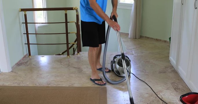 Middle aged brunette man cleaning floor with vacuum cleaner