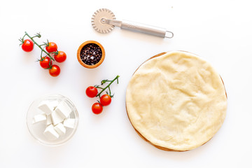 Process of cooking pizza. Pizza Margarita. Raw dough and filling. Cherry tomatoes, cheese mozzarella, spices near knife for pizza on white background top view mockup