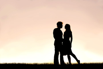 Happy Young Couple in Love Silhouetted Against Sunset in the Sky