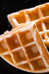woman hands prepare waffle for serving process.waffle made from dough and batter.tasty dessert sweets waffle served on daylight in cafe bokeh background.waffle with strawberry on black plate.