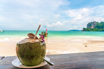 Coconut fruit drink at beautiful Tropical Beach blue ocean background with Traveler items  vacation travel accessories for holiday or long weekend a guide  choice idea for planning travel