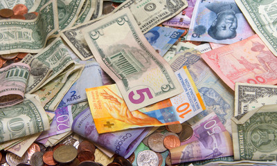 Close up on pile of many bank notes from various countries from around the world. U.S., German, Swiss, Canadian, Brazilian, Vietnamese, Mexican. Many countries represented in currency. Bills and coins