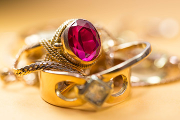 Real gold rings with diamond, chain, close up macro shot on yellow background.