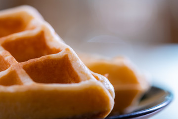 woman hands prepare waffle for serving process.waffle made from dough and batter.tasty dessert sweets waffle served on daylight in cafe bokeh background.waffle with strawberry on black plate.