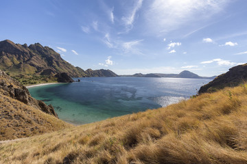 Fototapeta premium Arid grassland and pristine bay on Pulau Padar island in the Komodo National Park.