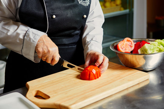 Chef cutting tomato on cutting board